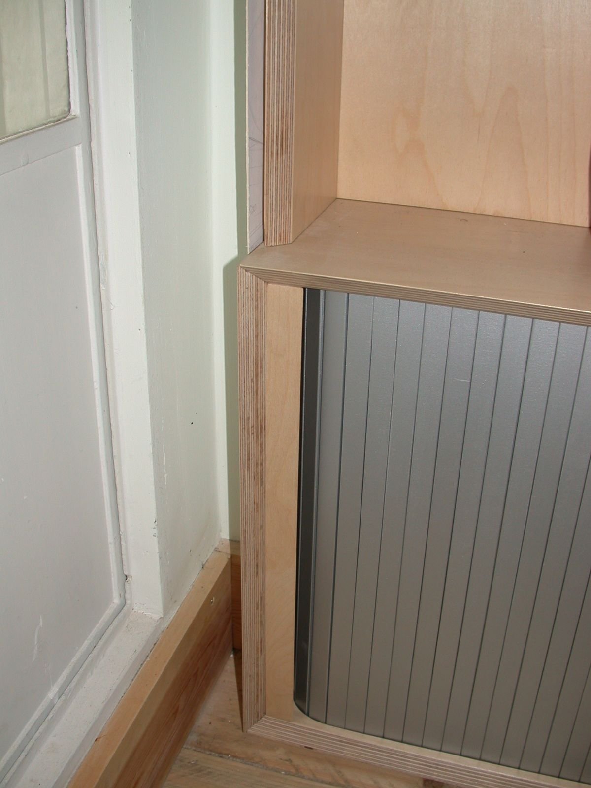 Silver tambour door closed in its birch ply frame