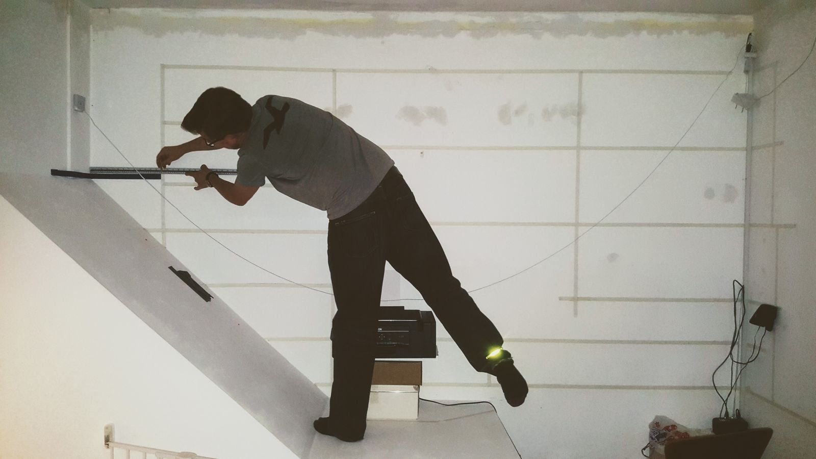 Simon marking out a shelf layout on a wall