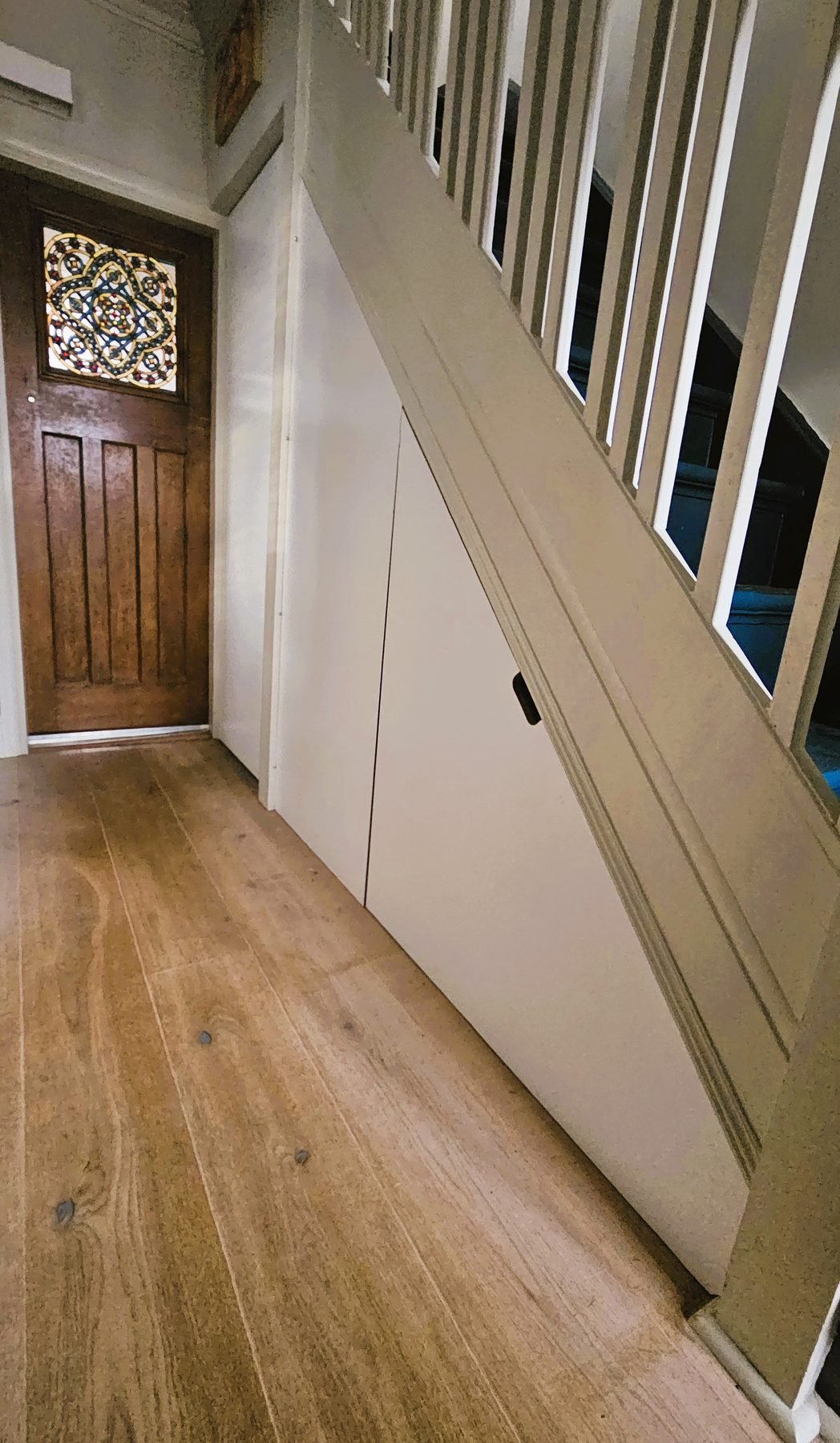 The hallway with the white understairs wall running towards the front door