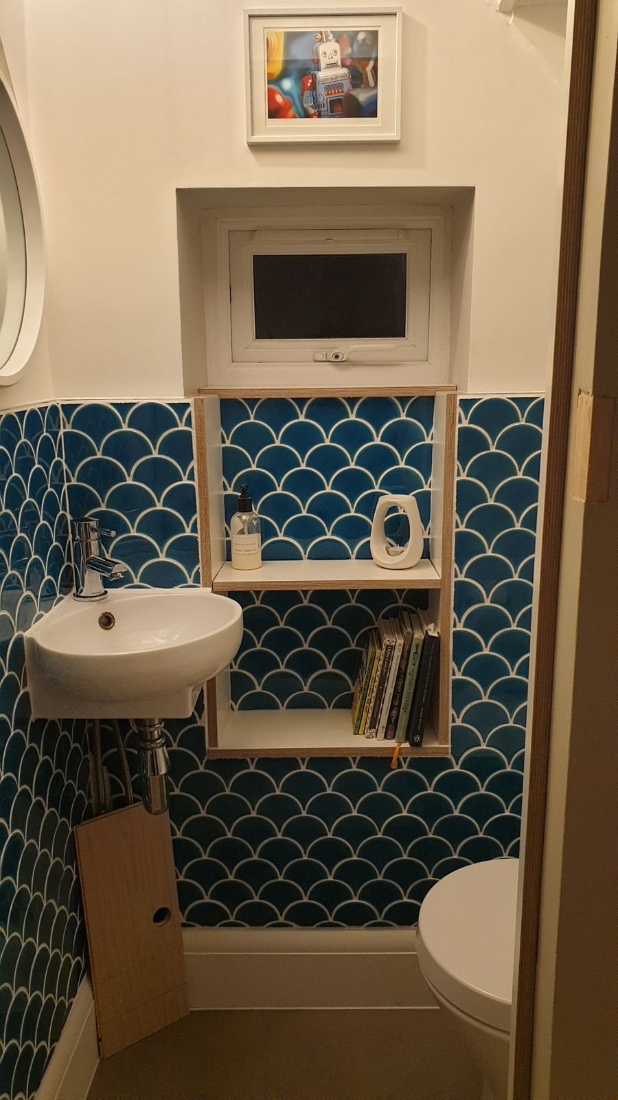 Plywood shelves beside the basin against blue scalloped tiles